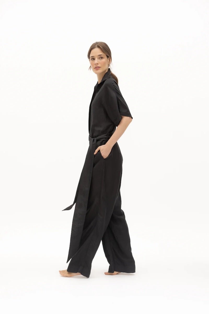 Women wearing a black jumpsuit with matching belt and a V-neck collar.