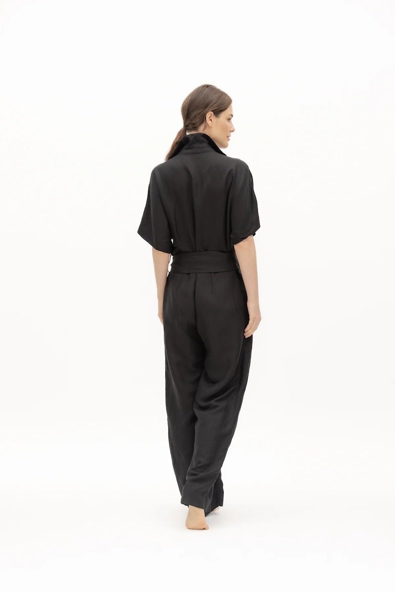 Women wearing a black jumpsuit with matching belt and a V-neck collar.