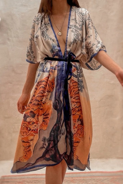 Woman wearing a floral and tiger print kimono with a plain background.