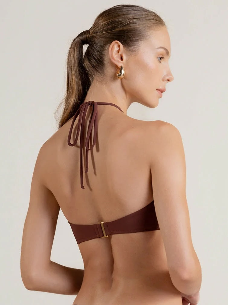 Woman wearing a brown bikini top with thin straps on a white background.