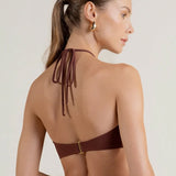 Woman wearing a brown bikini top with thin straps on a white background.