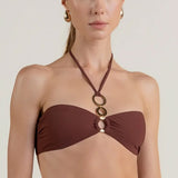 Woman wearing a brown bikini halter top with a unique circular design on a plain background.