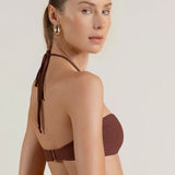 Woman wearing a brown bikini top against a plain background.