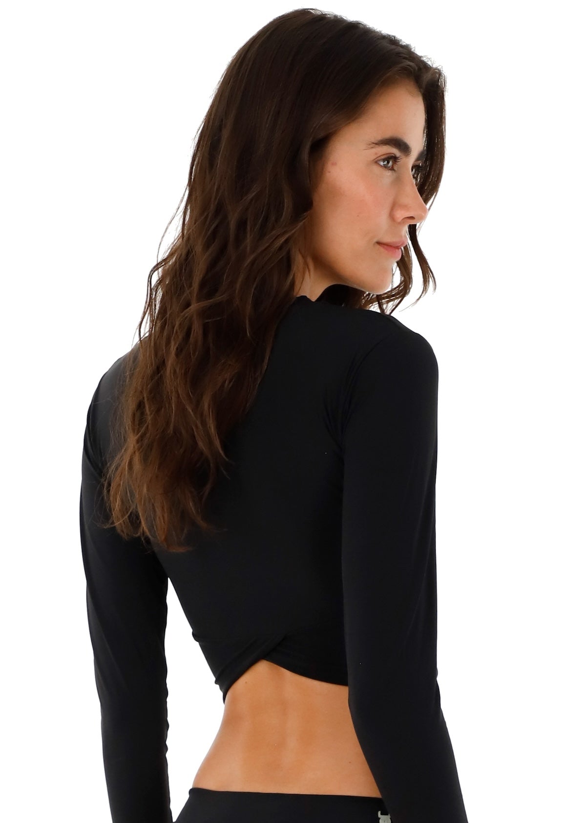 Woman wearing a black rashguard and swimsuit bottoms. She's standing against a white background. The purpose of this image is to highlight the swimsuit.