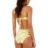 Back of a woman wearing a swimsuit with a yellow animal print. She's standing against a white background. The purpose of this image is to highlight the swimsuit.