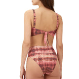 The back view of a woman wearing a stylish Costa Bikini Top. The bikini top features a striking tie-dye pattern in shades of pink and orange, contributing to its vibrant aesthetic.