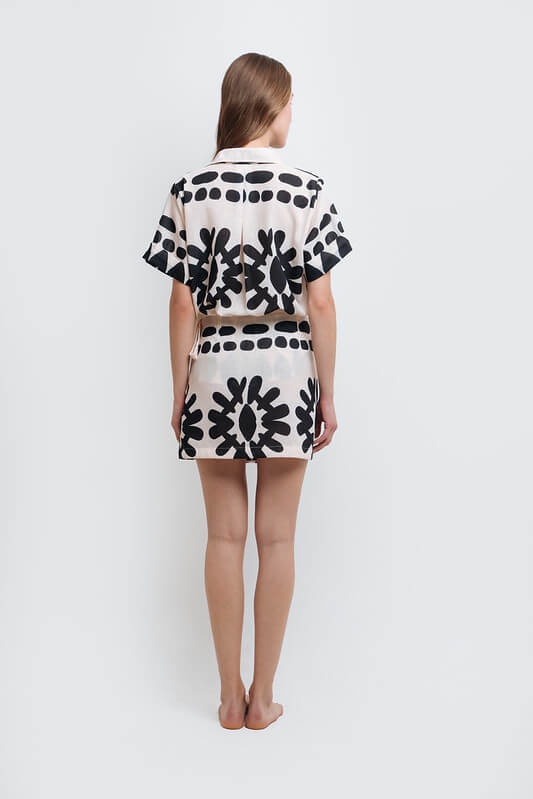 Back of a model wearing a stylish black and white abstract print shirt and skirt set made from high-quality polyester with a linen-like feel