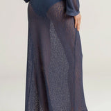 Person wearing a dark blue sheer maxi skirt with a plain background.
