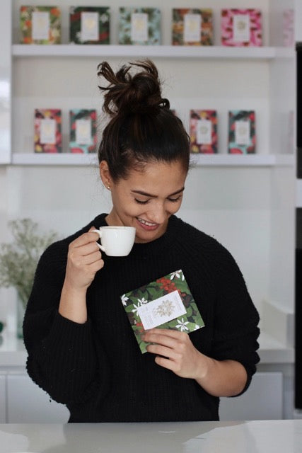 A person drinking coffee while holing Keru Chocolates coffee flavored chocolate bar.