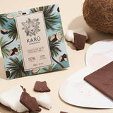 A chocolate bar package with 'Karü Chocolates' branding, showing pieces of chocolate and a coconut in the background, indicating the flavor of the chocolate.