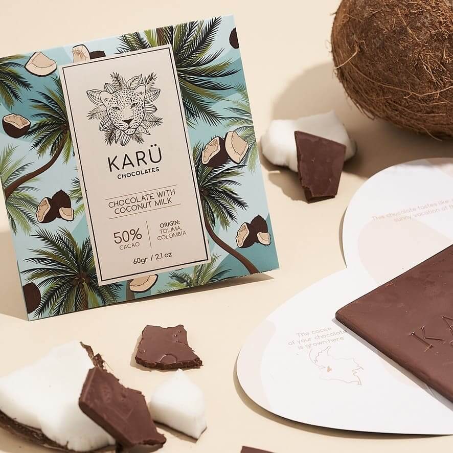 A chocolate bar package with 'Karü Chocolates' branding, showing pieces of chocolate and a coconut in the background, indicating the flavor of the chocolate.