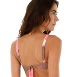 Image of a woman wearing a tie die swimsuit top by Malai Swimwear. She's looking to the side and standing on a white background. The purpose of this image is to highlight the bikini.