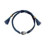 Image of an adjustable bracelet made of braided string and with a face charm on it. It's set against a white background. The purpose of this image is to highlight the jewelry by PAJAROLIMON.