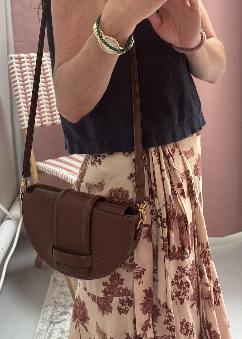 Person wearing a brown leather handbag with a floral skirt and black top.