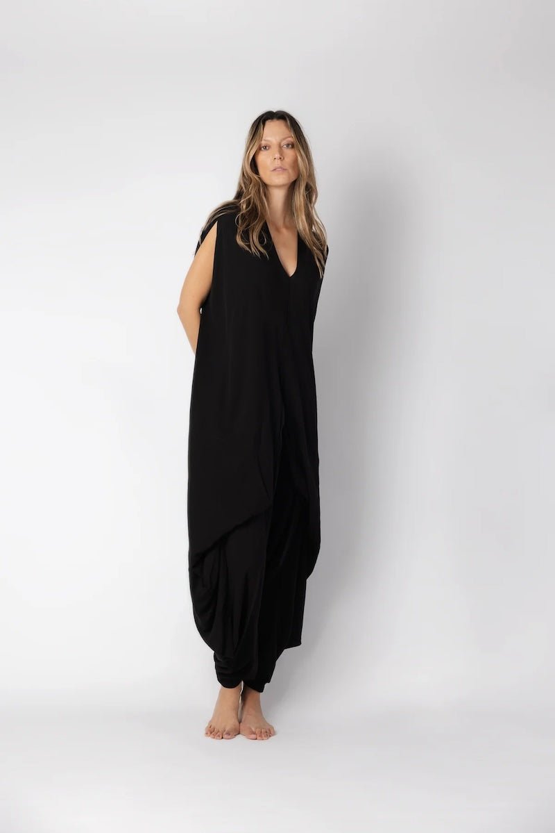 Image of woman wearing a flowy jumpsuit against a white background. The purpose of this image is to highlight the jumpsuit from NAOS, which is for sale at EVAMAIA boutique in Studio City, CA.