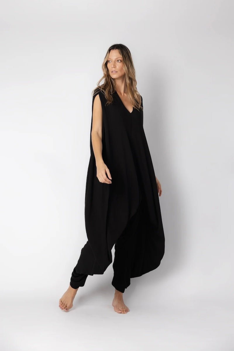 Image of woman wearing a flowy jumpsuit against a white background. The purpose of this image is to highlight the jumpsuit from NAOS, which is for sale at EVAMAIA boutique in Studio City, CA.