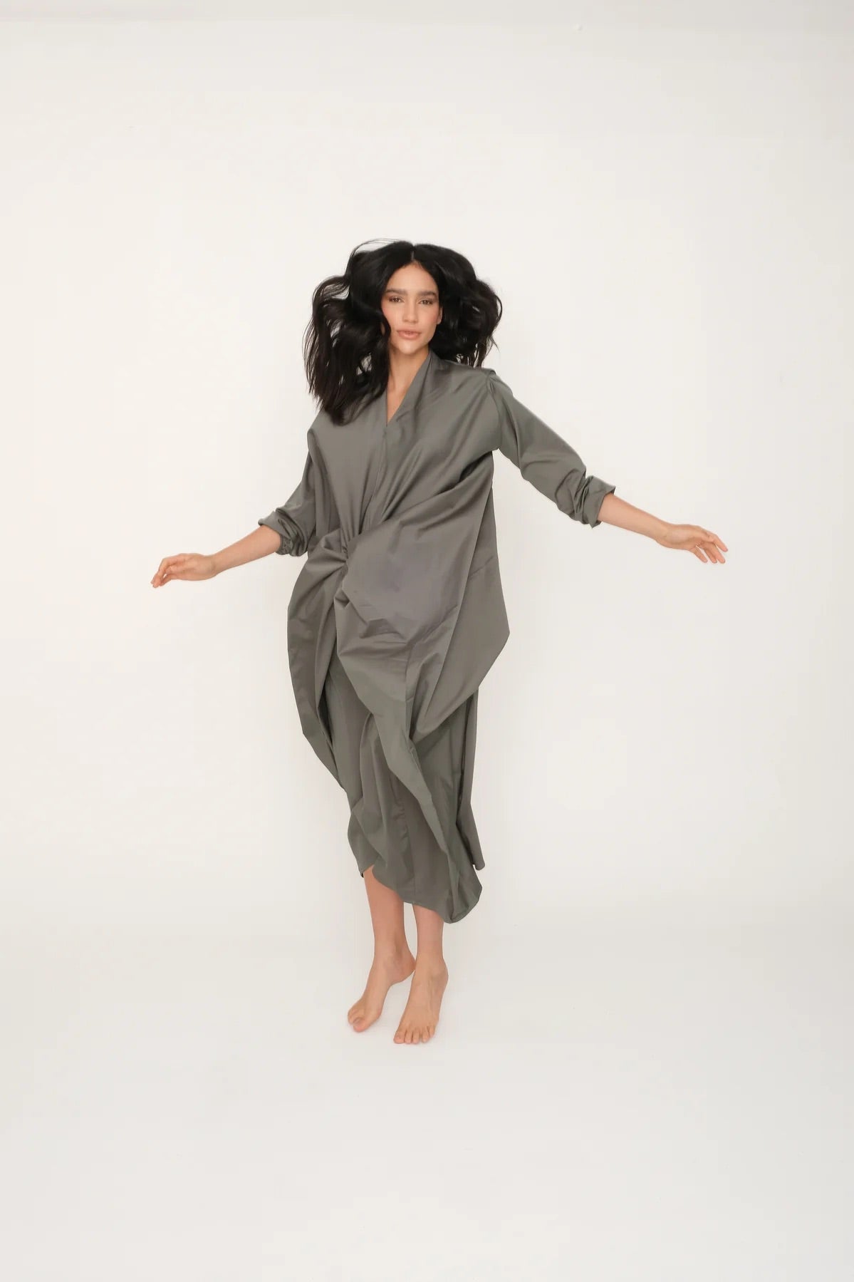 Woman wearing the green Miaroma dress against a white background