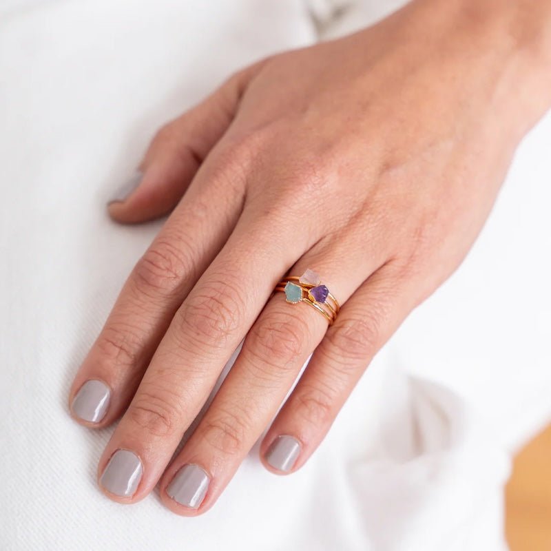 Close up image of a woman wearing 3 dainty gold rings with a raw stones on them. The purpose of this image is to highlight the jewelry because it is for sale at EVAMAIA boutique in Studio City, CA and online.