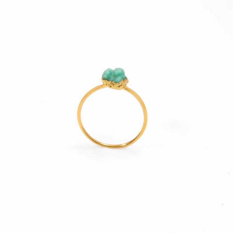 Close up image of a dainty gold ring with a raw emerald stone on it. The purpose of this image is to highlight the ring because it is for sale at EVAMAIA boutique in Studio City, CA and online.