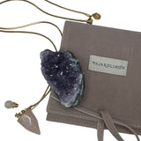Image of a gold necklace holding a rose quartz perfume bottle. The purpose of this image is to highlight the necklace. This necklace is made in Colombia by Pajarolimon and sold at EVAMAIA boutique.