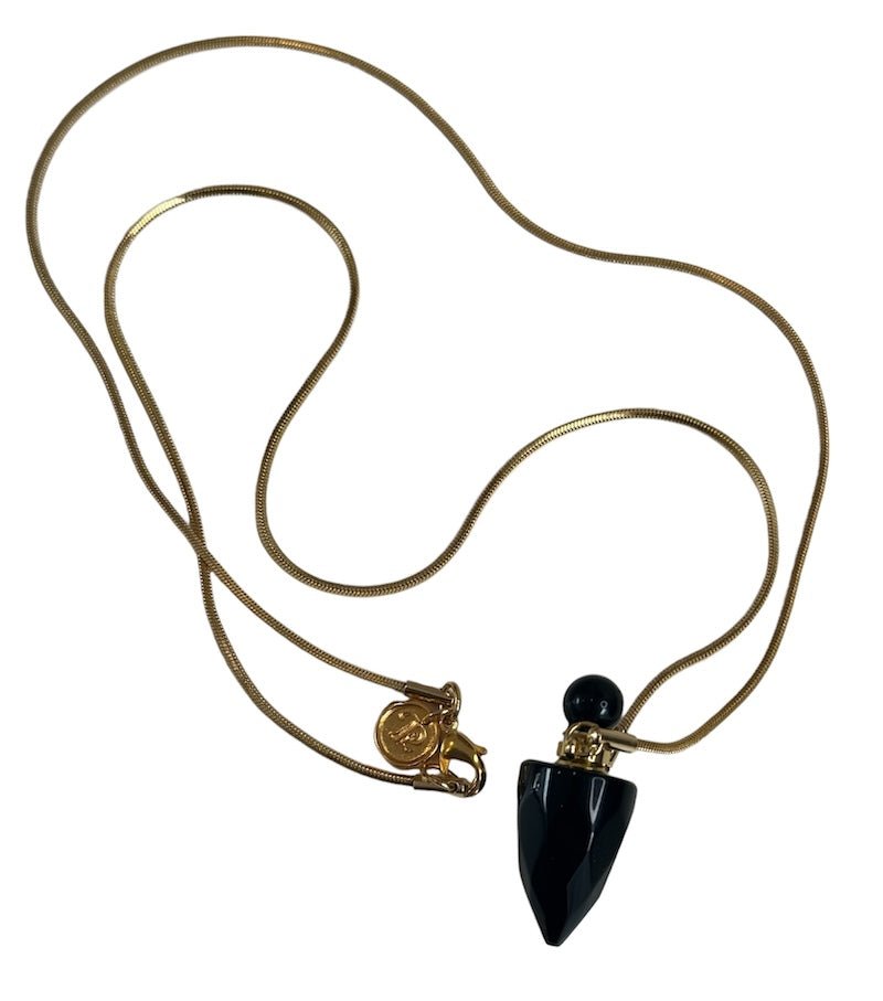 Image of a gold necklace holding a black obsidian perfume bottle. The purpose of this image is to highlight the necklace. This necklace is made in Colombia by Pajarolimon and sold at EVAMAIA boutique.