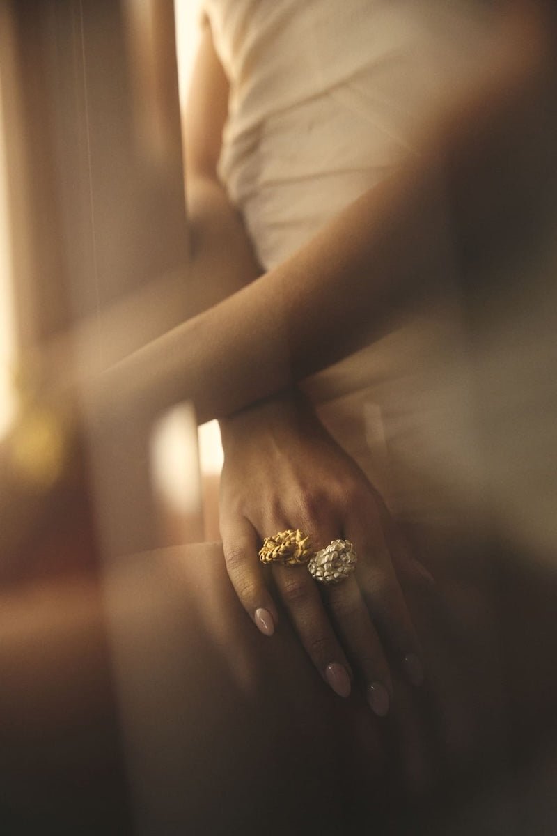 Close up image of a woman wearing two rings. One gold and one silver. The purpose of this image is to highlight the rings by ALMA Jewelry.