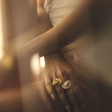Close up image of a woman wearing two rings. One gold and one silver. The purpose of this image is to highlight the rings by ALMA Jewelry.