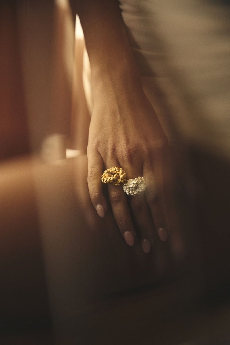 Close up image of a woman wearing two rings. One gold and one silver. The purpose of this image is to highlight the rings by ALMA Jewelry.