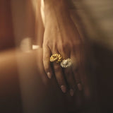 Close up image of a woman wearing two rings. One gold and one silver. The purpose of this image is to highlight the rings by ALMA Jewelry.