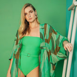 Image of a woman wearing a green one-piece swimsuit and a matching cover-up. She's standing against a green background and looking at the camera.