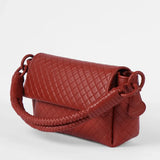 Red quilted handbag on a white background.