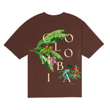 Brown t-shirt with 'Colombia' and floral design of banana plant and a coffee plant on a white background.