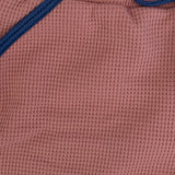 Close-up of a waffle textured pink fabric with blue trim.