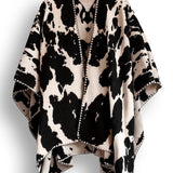 Black and white cow patterned poncho on a white background.