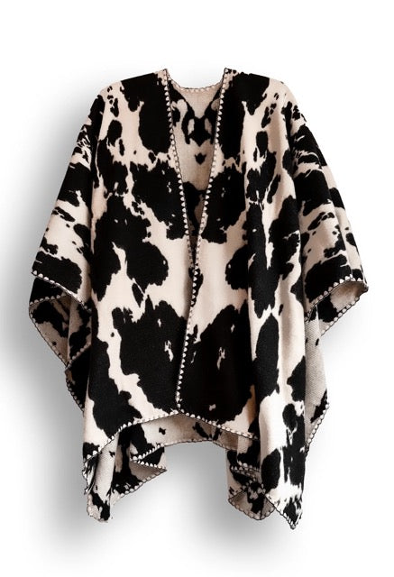 Black and white cow patterned poncho on a white background.