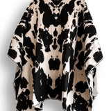 Black and white cow patterned poncho on a white background.
