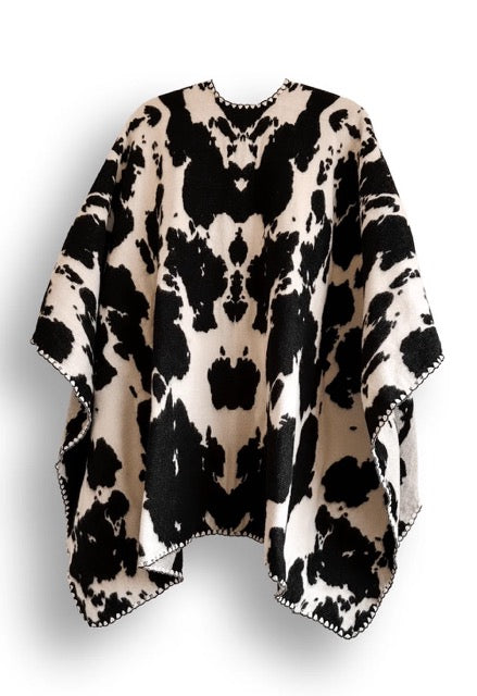 Black and white cow patterned poncho on a white background.