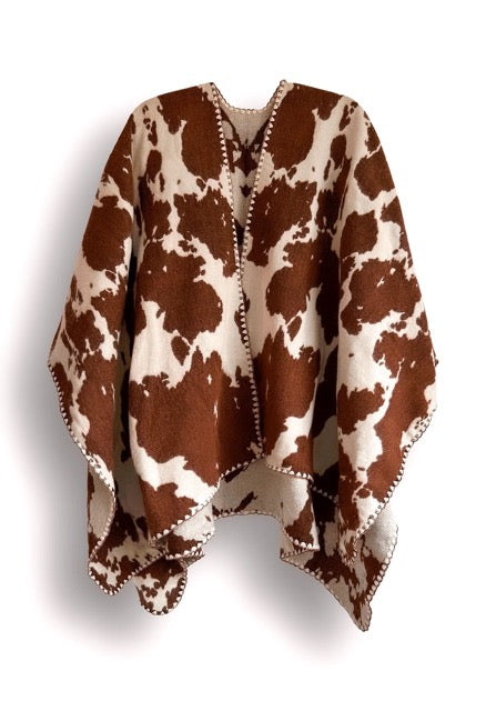 Brown and white cow patterned poncho on a white background.