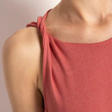 Close up image of a woman wearing a rose colored pajama set. The sleeves on the top look folded. She's standing in front of a white wall. The purpose of this image is to highlight the folded sleeve detail.