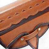 A two-toned brown leather crossbody saddle bag with multiple pockets and hardware accents, handmade in Colombia.