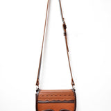 A two-toned brown leather crossbody saddle bag with multiple pockets and hardware accents, handmade in Colombia.