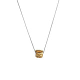 Image of a silver necklace holding a gold charm with round and linear designs to it. The purpose of this image is to highlight the Pajarolimon necklace because it is for sale at EVAMAIA Boutique in Studio City, CA.