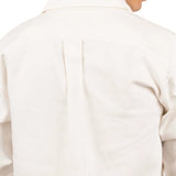 Close up of the back of a man wearing a white cotton jacket. He's standing behind a white background. The purpose of this image is to highlight the jacket, which is made in Colombia and available at EVAMAIA boutique.