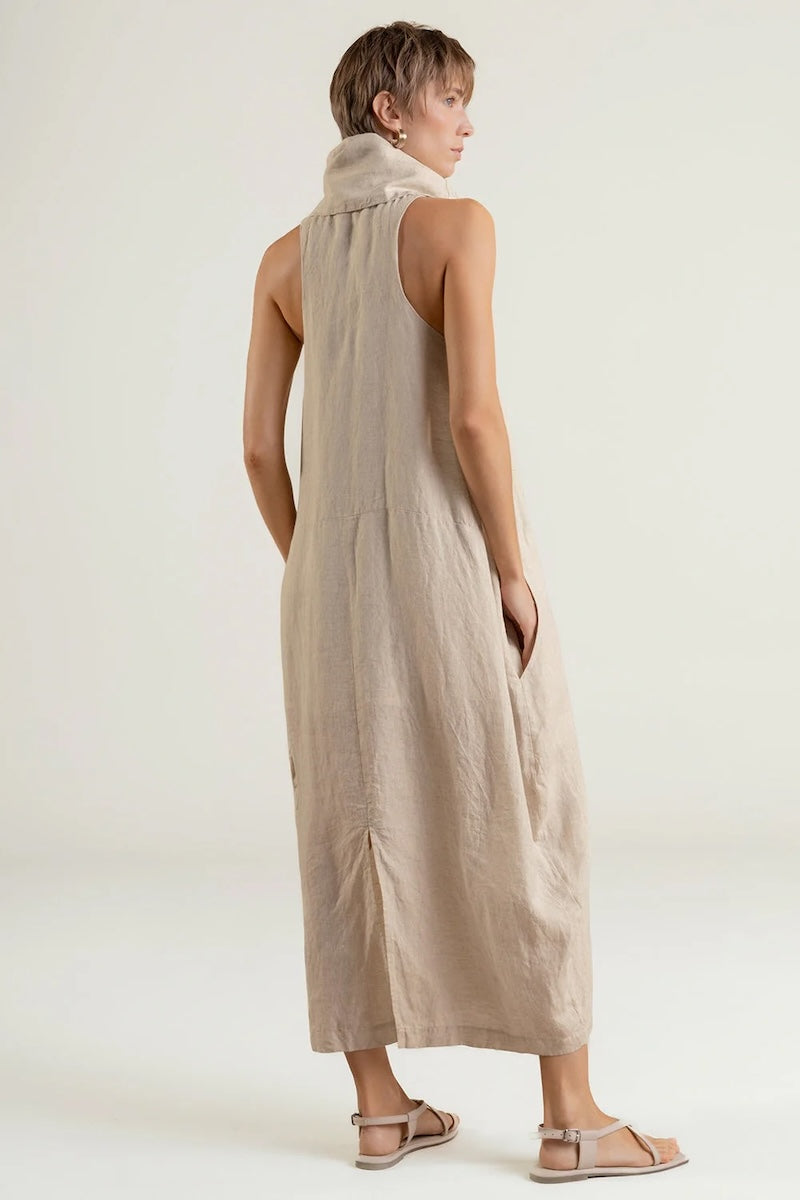 Woman wearing a beige sleeveless dress against a white background.