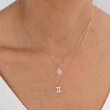 Close up image of a woman's neckline. She's wearing two necklaces. One has a charm of a Gemini zodiac sign and the other has a Moonstone. The purpose of this image is to highlight the necklaces, which are made in Colombia and sold in Studio City, at EVAMAIA boutique.