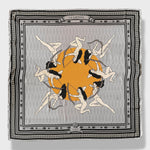 La Gaitana Scarf by Plissé. Image of 8 Cacica Gaitana in a circle over a yellow dot. The whole deign over over a light grey geometric pattern with a frame like border and arrow border. The overall tone of the scarf is a washed out grey.