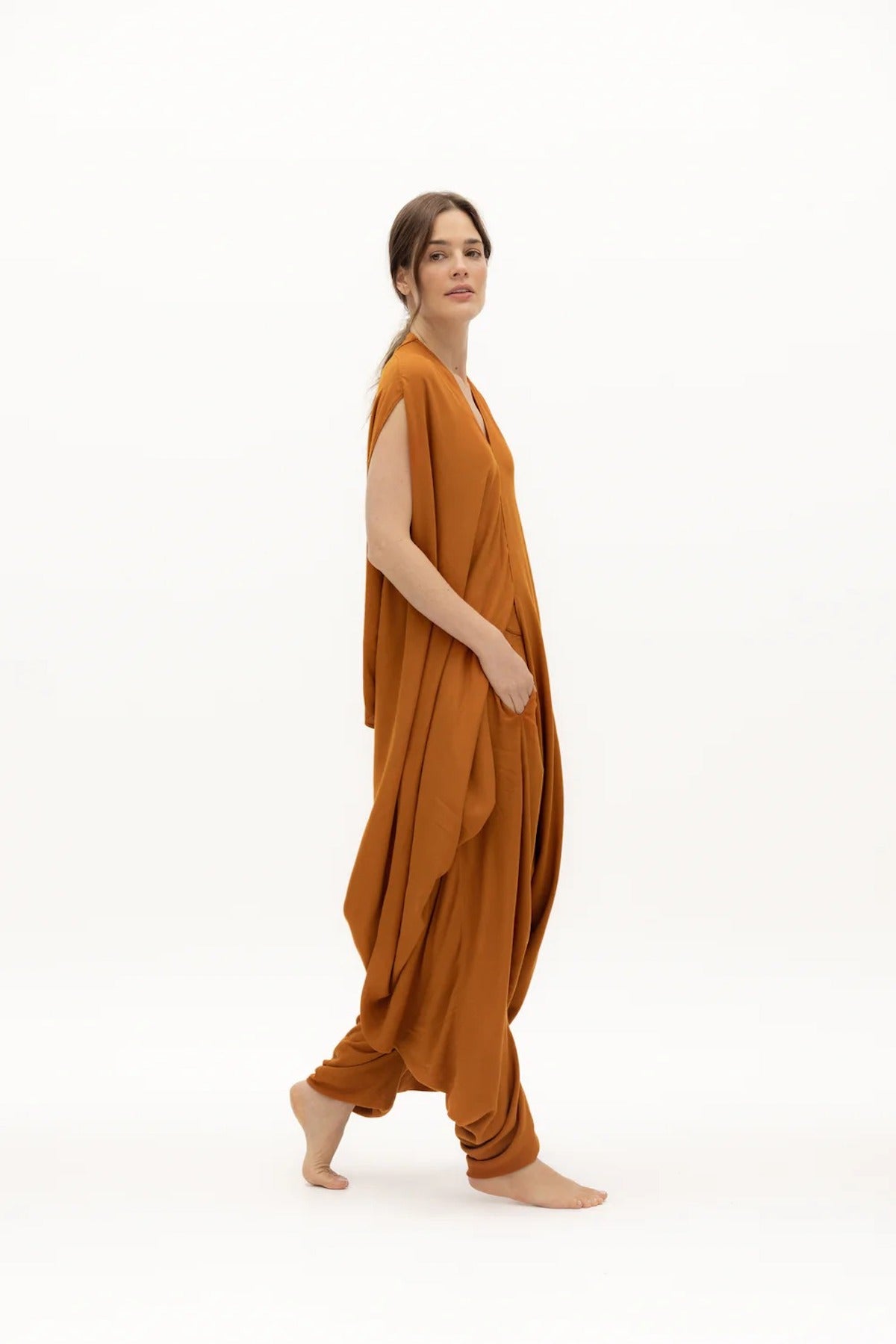 Image of woman wearing a flowy jumpsuit against a white background. The purpose of this image is to highlight the jumpsuit from NAOS, which is for sale at EVAMAIA boutique in Studio City, CA.