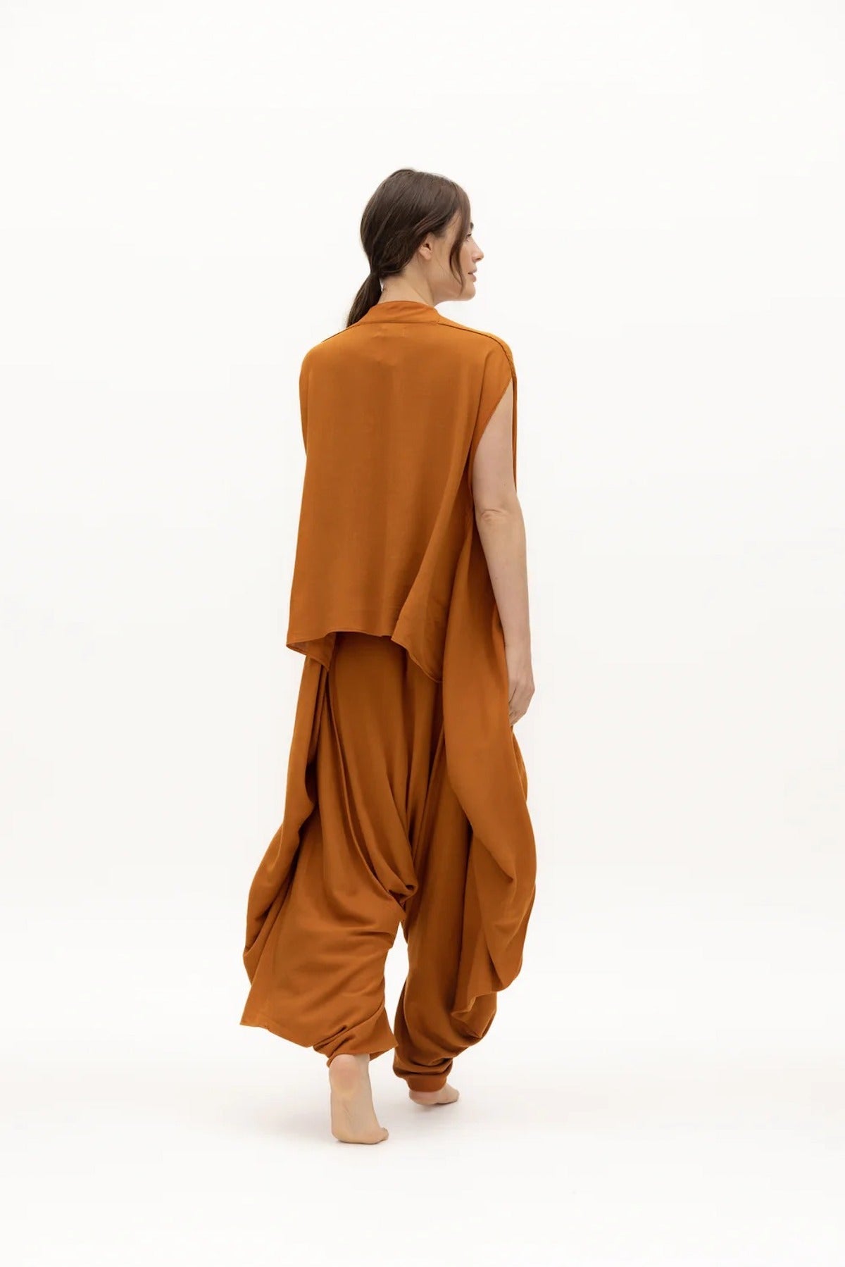 Image of woman wearing a flowy jumpsuit against a white background. The purpose of this image is to highlight the jumpsuit from NAOS, which is for sale at EVAMAIA boutique in Studio City, CA.