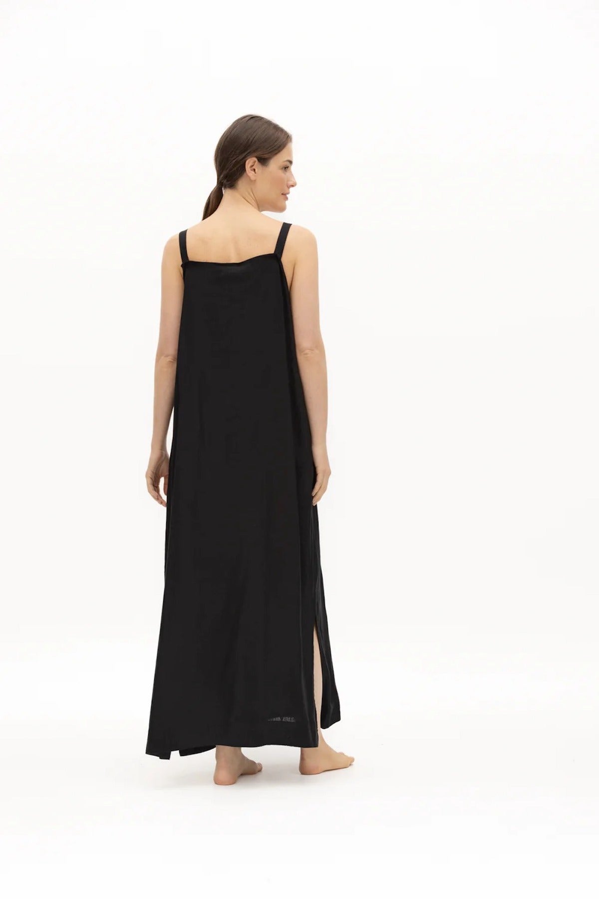 Image of a woman wearing a long dress with pockets and spaghetti straps that was made in Colombia by NAOS. The purpose of this image is to highlight the dress, which is for sale at EVAMAIA boutique in Studio City, CA and online.