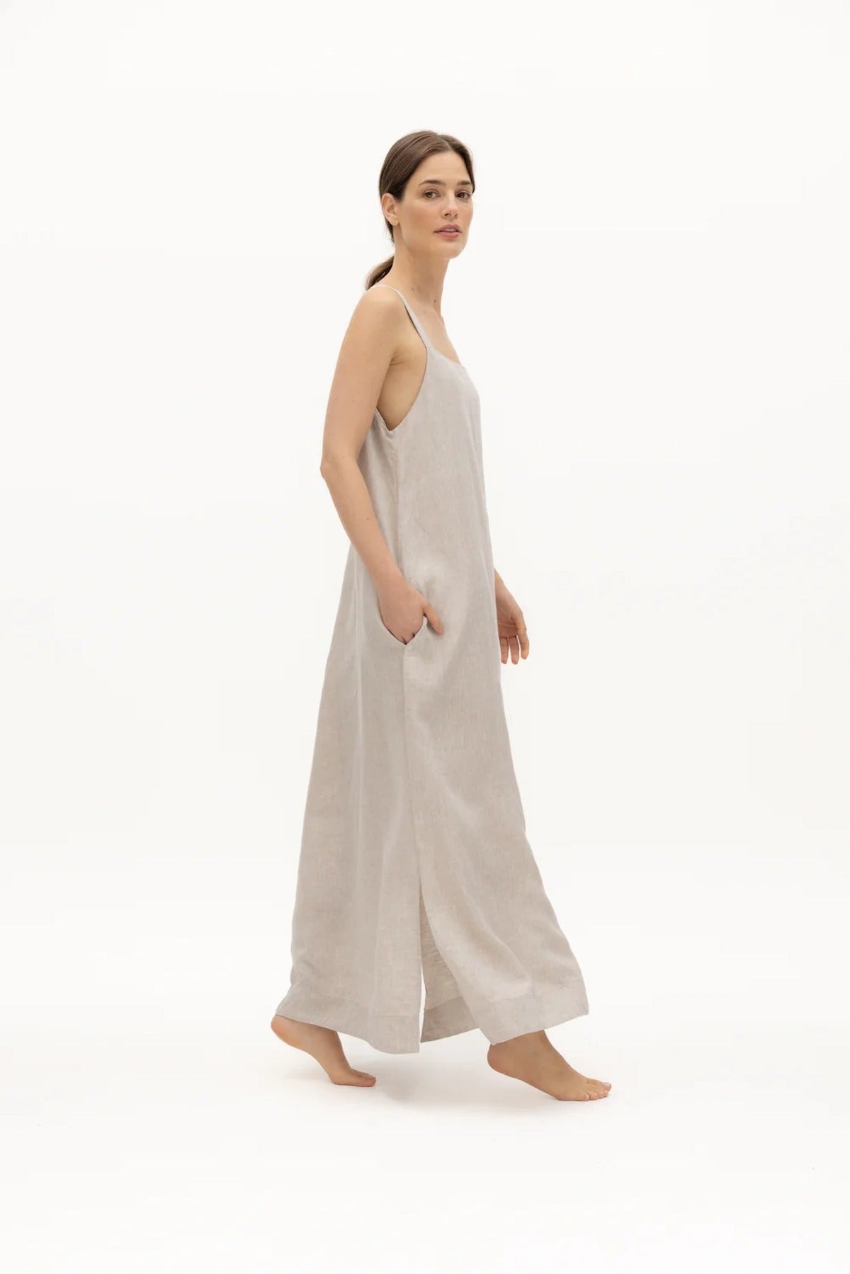 Image of a woman wearing a long dress with pockets and spaghetti straps that was made in Colombia by NAOS. The purpose of this image is to highlight the dress, which is for sale at EVAMAIA boutique in Studio City, CA and online.